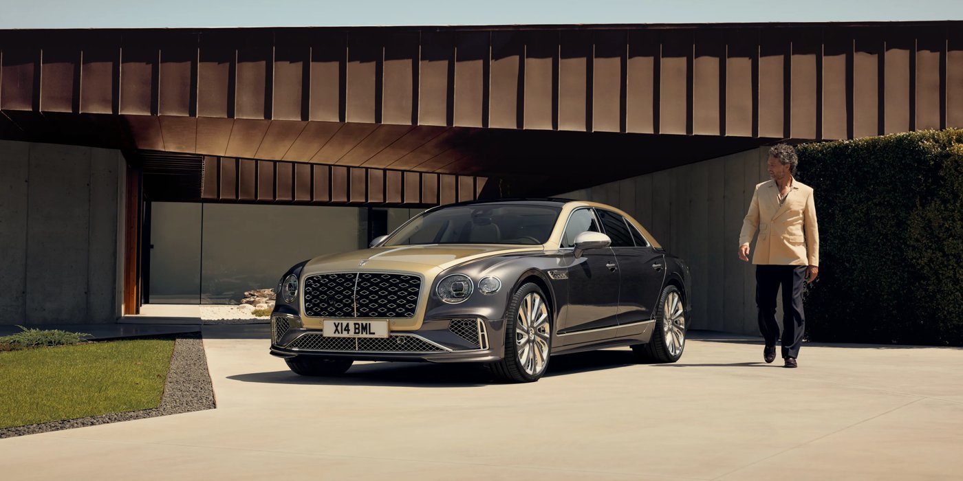 Bentley Riyadh Bentley New Flying Spur Mulliner V8 hybrid sedan front three quarters in Rose Gold over Magnetic paint, parked near modern home