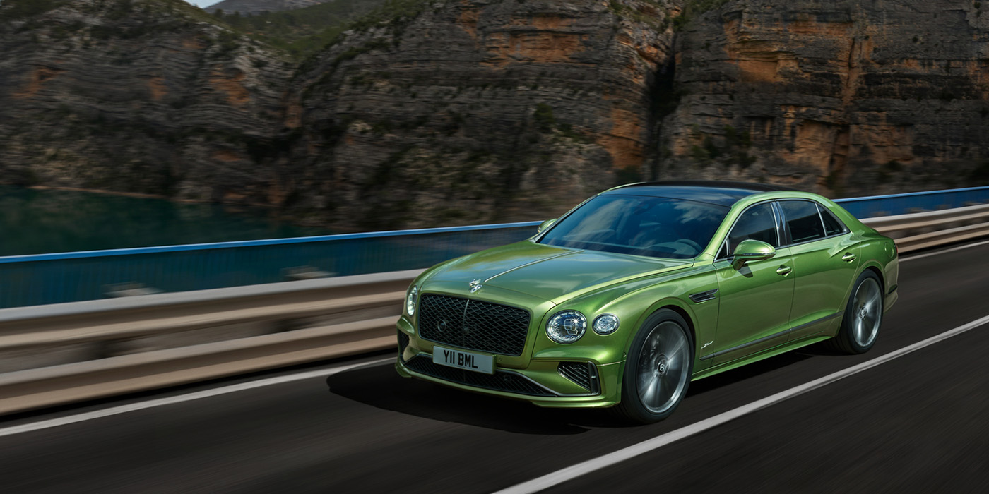 Bentley Riyadh Bentley New Flying Spur Speed v8 hybrid sedan driving dynamically on a mountain road in Tourmaline Green paint