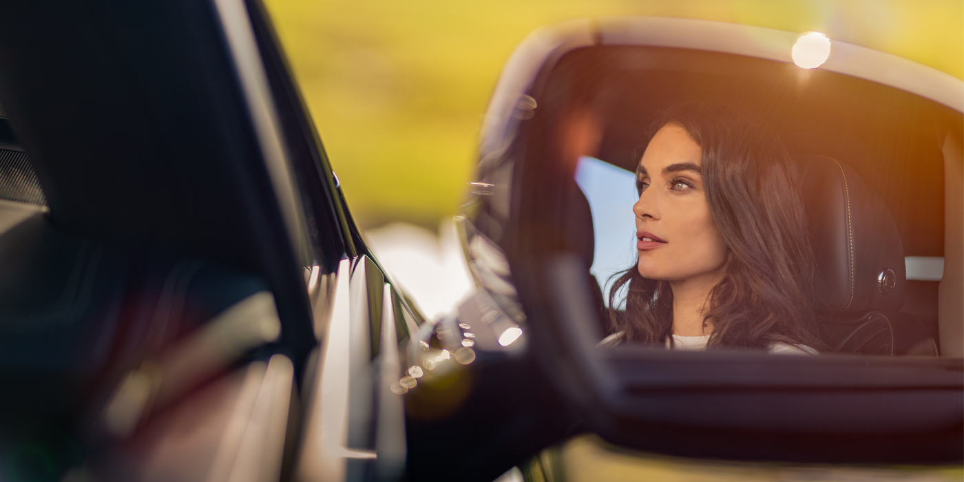 Bentley Riyadh profile of dark haired woman's face in mirror of Bentley car in sunlight