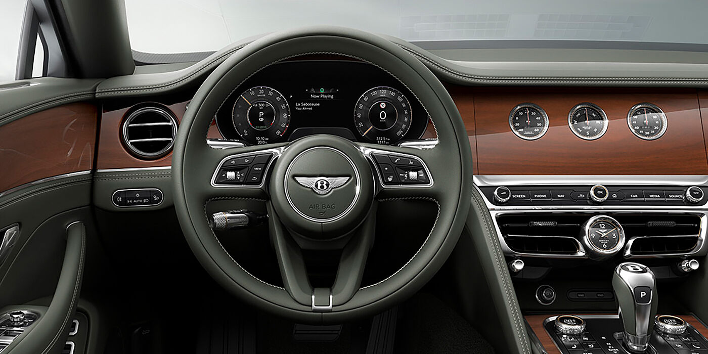 Bentley Riyadh New Bentley Flying Spur sedan front cabin in Cumbrian Green hide and Crown Cut walnut veneer showing steering wheel and Rotating Display with three clocks on face
