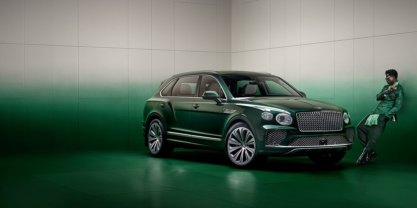 Bentley Riyadh Wisdom K leans against wall next to Bentley Bentayga Extended Wheelbase Atelier Edition SUV in Light Emerald green paint