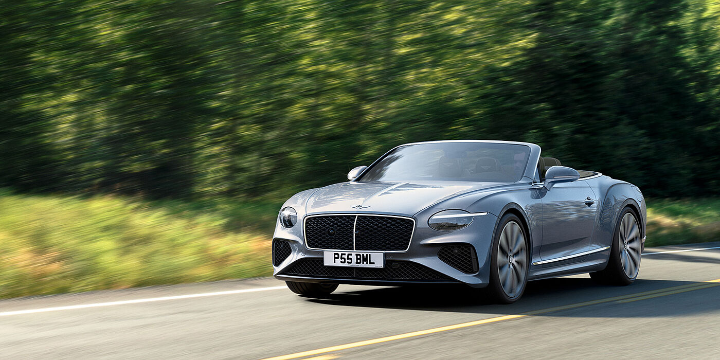 Bentley Riyadh New Bentley Continental GTC convertible front view in Silverlake paint with 22 inch ten spoke wheels, driving dynamically on a country road