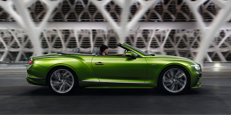 Bentley Riyadh Bentley Continental GTC Speed convertible side profile in Tourmaline Green paint driving dynamically on a bridge at night