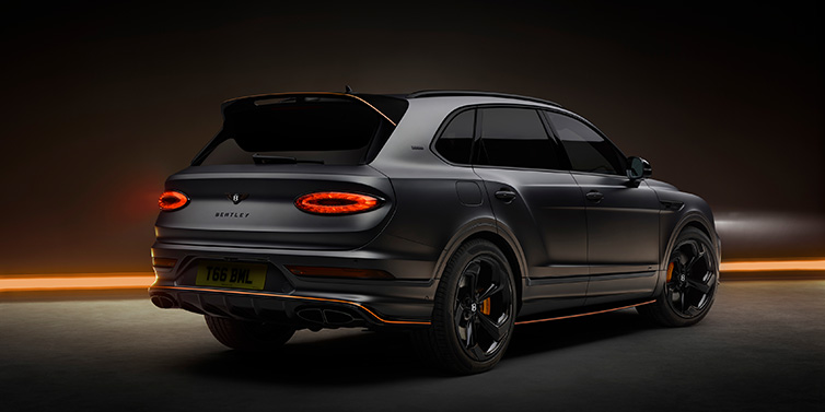 Bentley Riyadh Bentley Bentayga S Black Edition SUV rear three quarter in Anthracite Satin paint against a dark red and yellow background