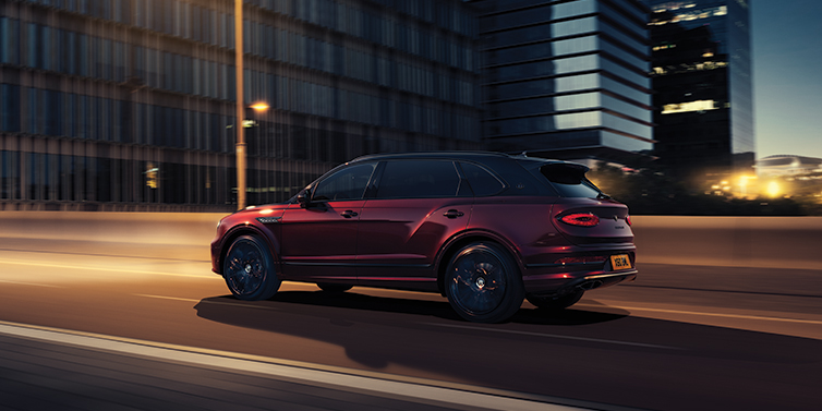 Bentley Riyadh Bentley Bentayga Extended Wheelbase Mulliner SUV in Cricket Ball red paint driving dynamically in city at night