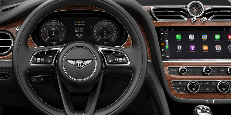 Bentley Riyadh Bentley Bentayga SUV front interior detail of steering wheel and driver screens surrounded by Beluga black hide and Crown Cut Walnut veneer